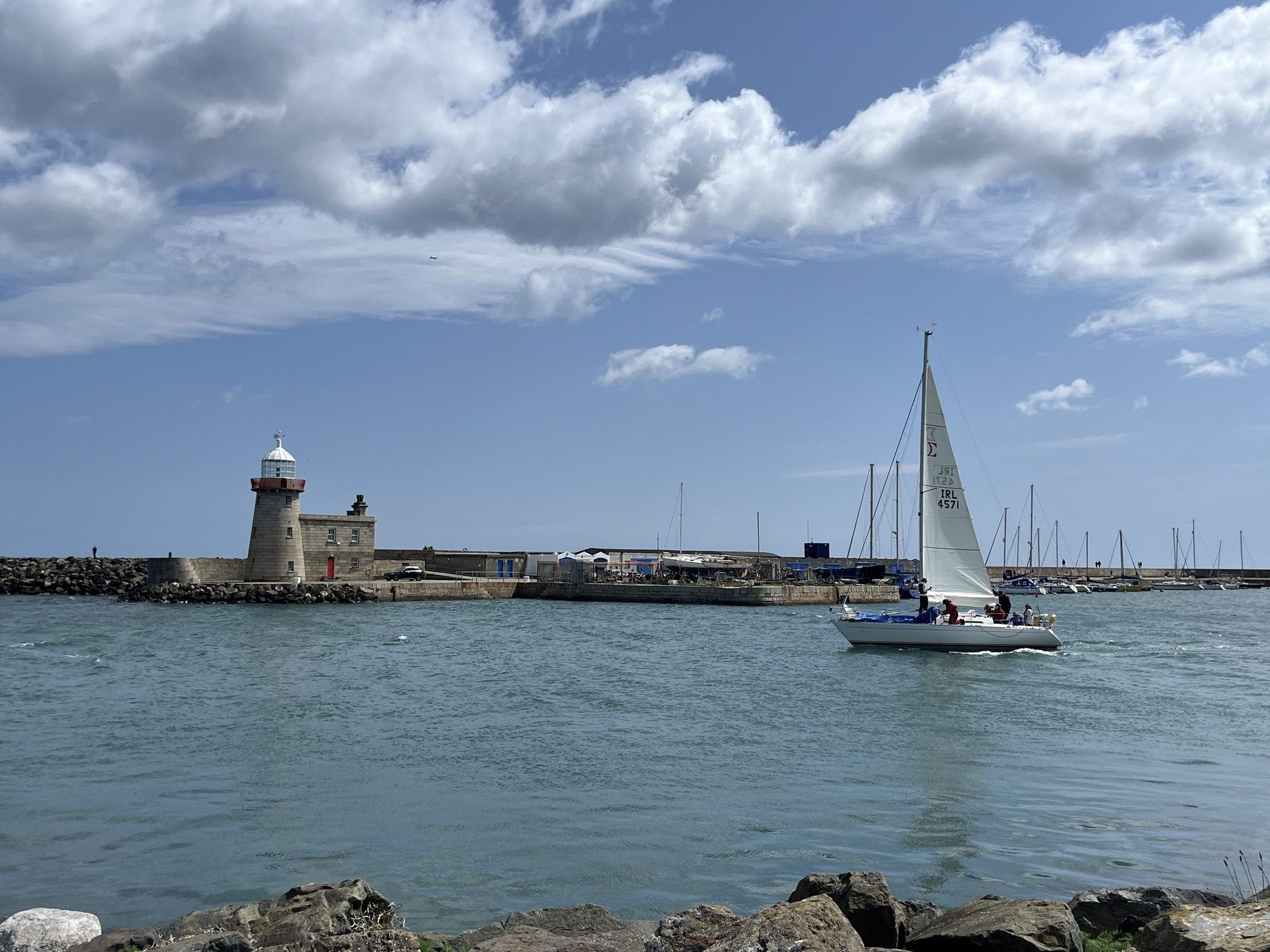 A sailing boat passing the lighthouse at the mouth of Howth Harbour